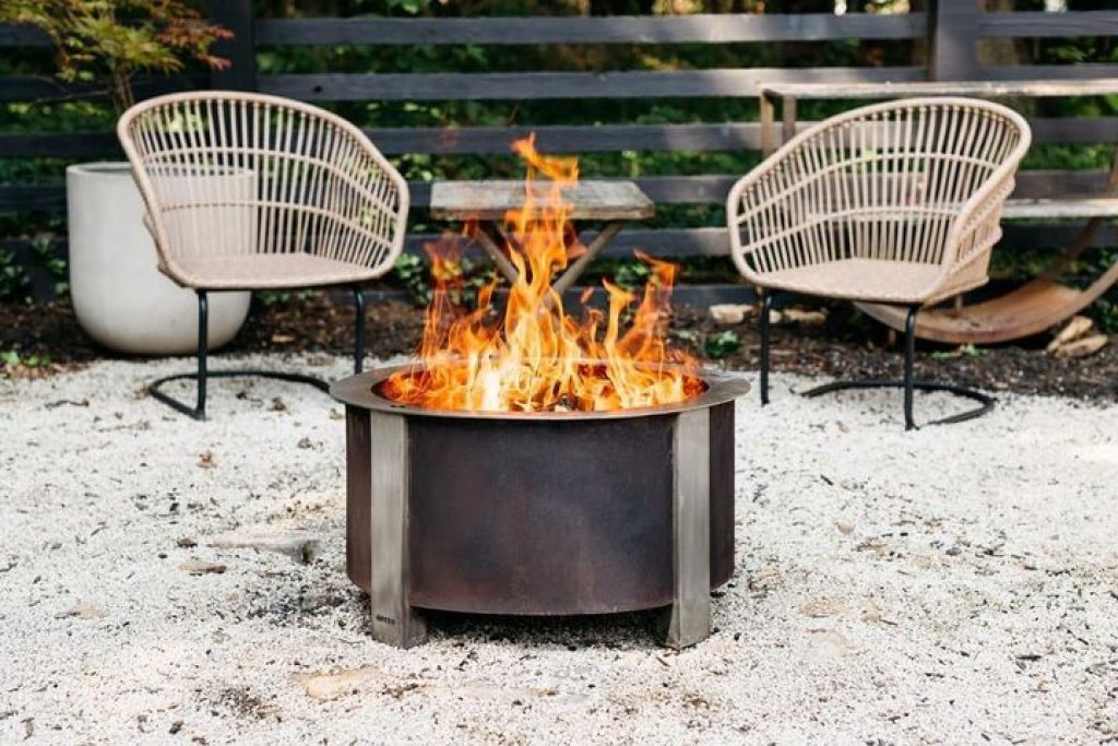 A backyard with two chairs and a Breeo X Series 24 Smokeless Fire Pit