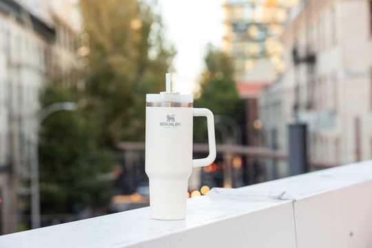 a white stanley quencher tumbler sitting on a railing