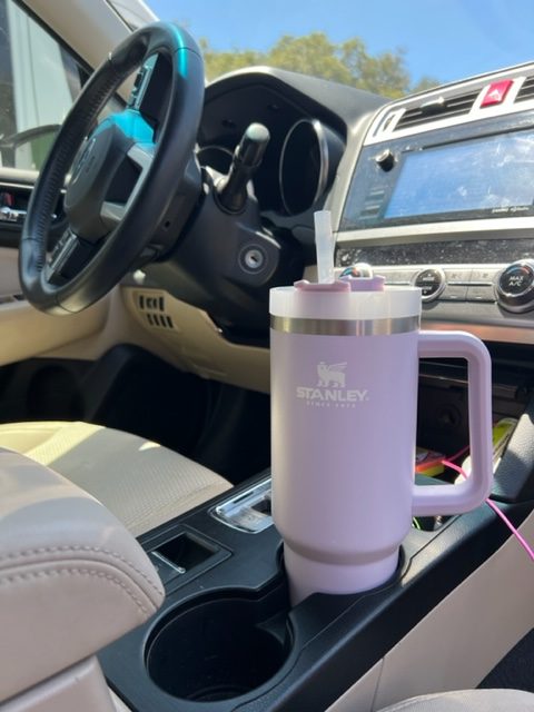 a stanley quencher tumbler in a car cupholder