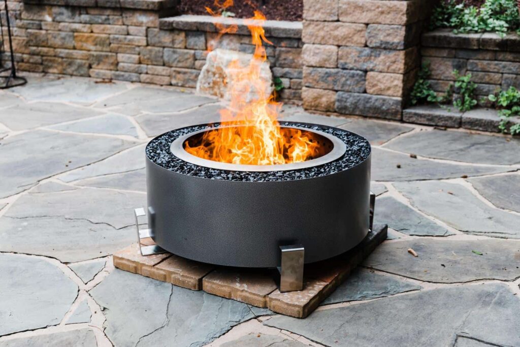 A backyard with the Breeo Luxeve fire pit on pavers