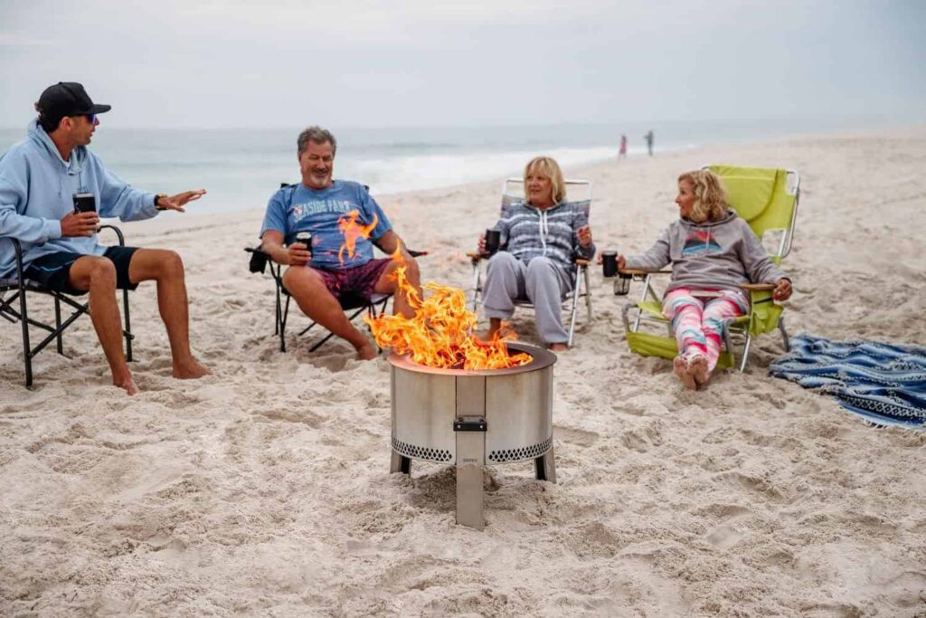 A family at the beach sitting around a Breeo Y Series fire pit